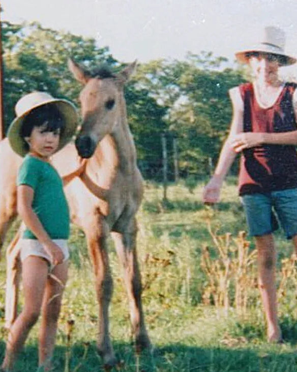 Two children with a horse in a grassy field